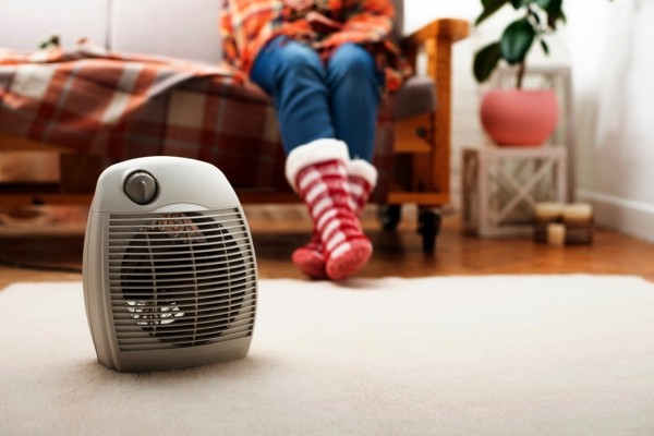 Person sitting on couch by space heater.